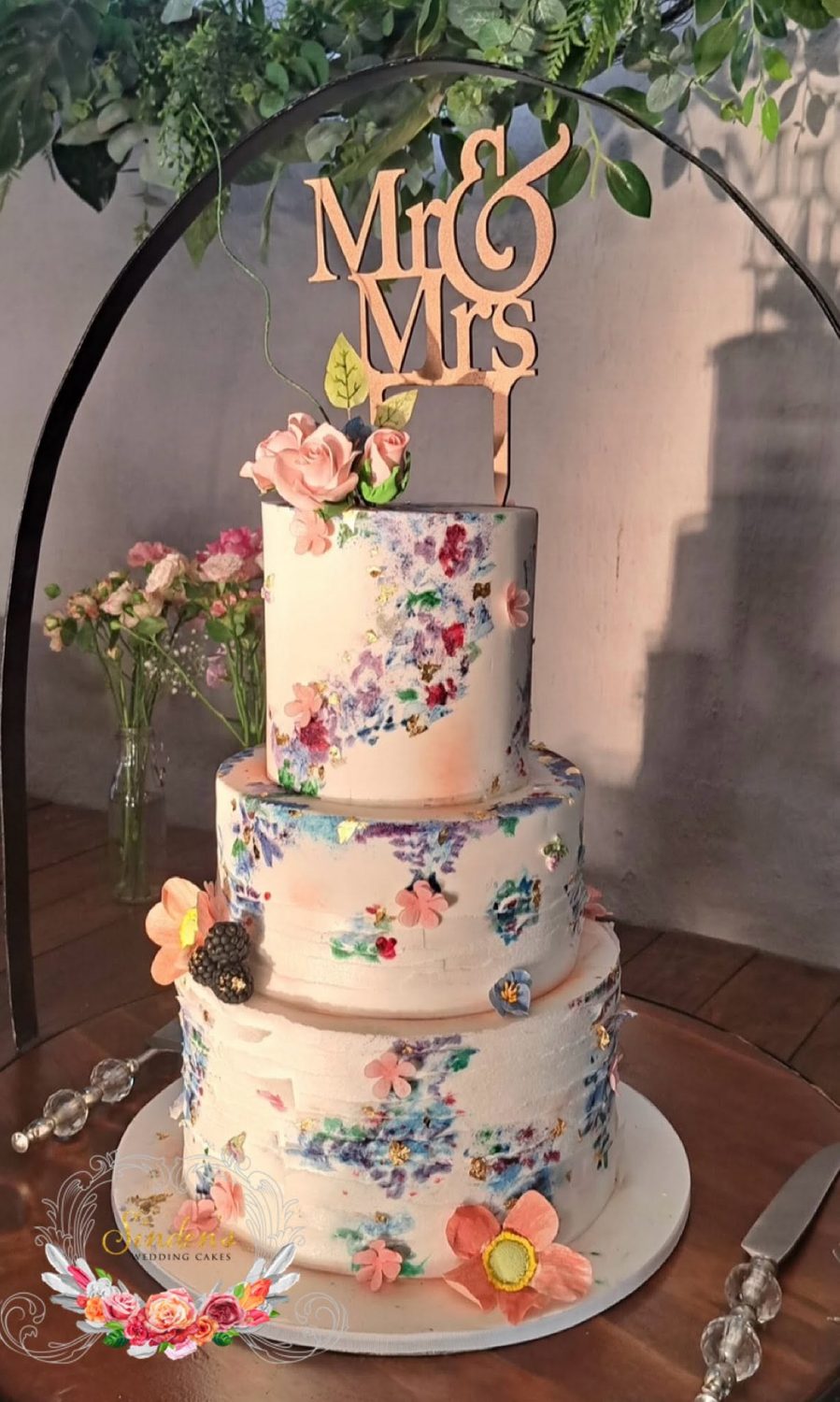 Tall white wedding cake with cascading florals and candlelight