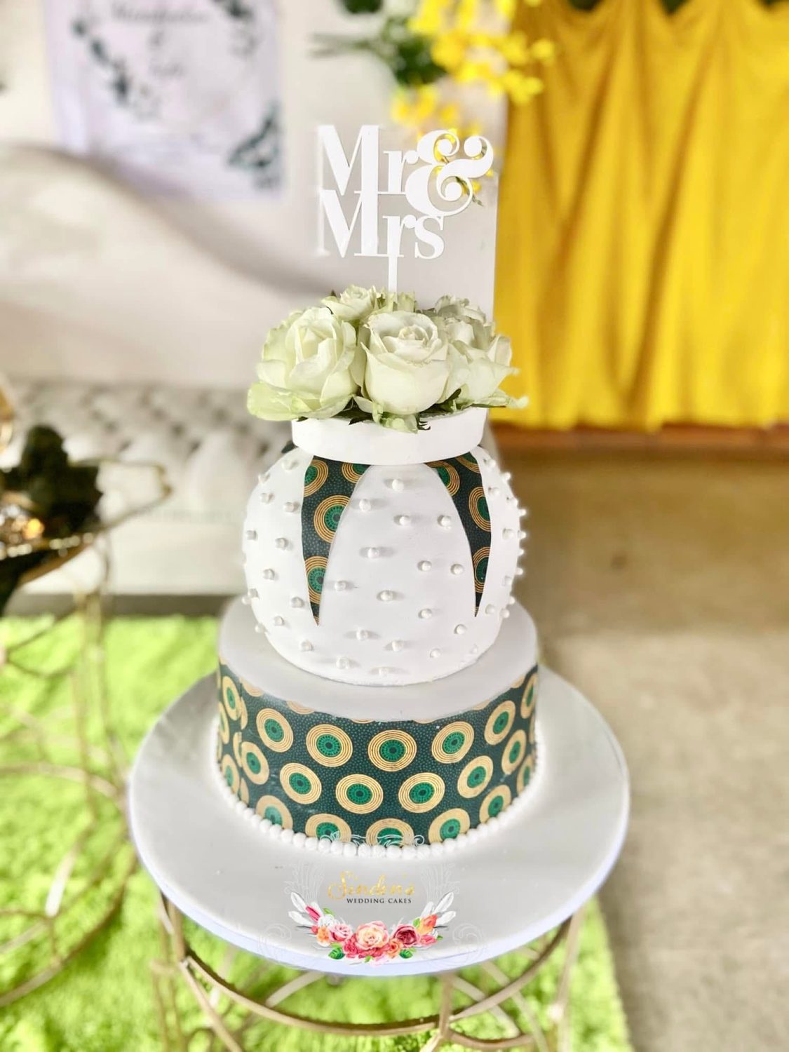 White cake with green ribbon and florals
