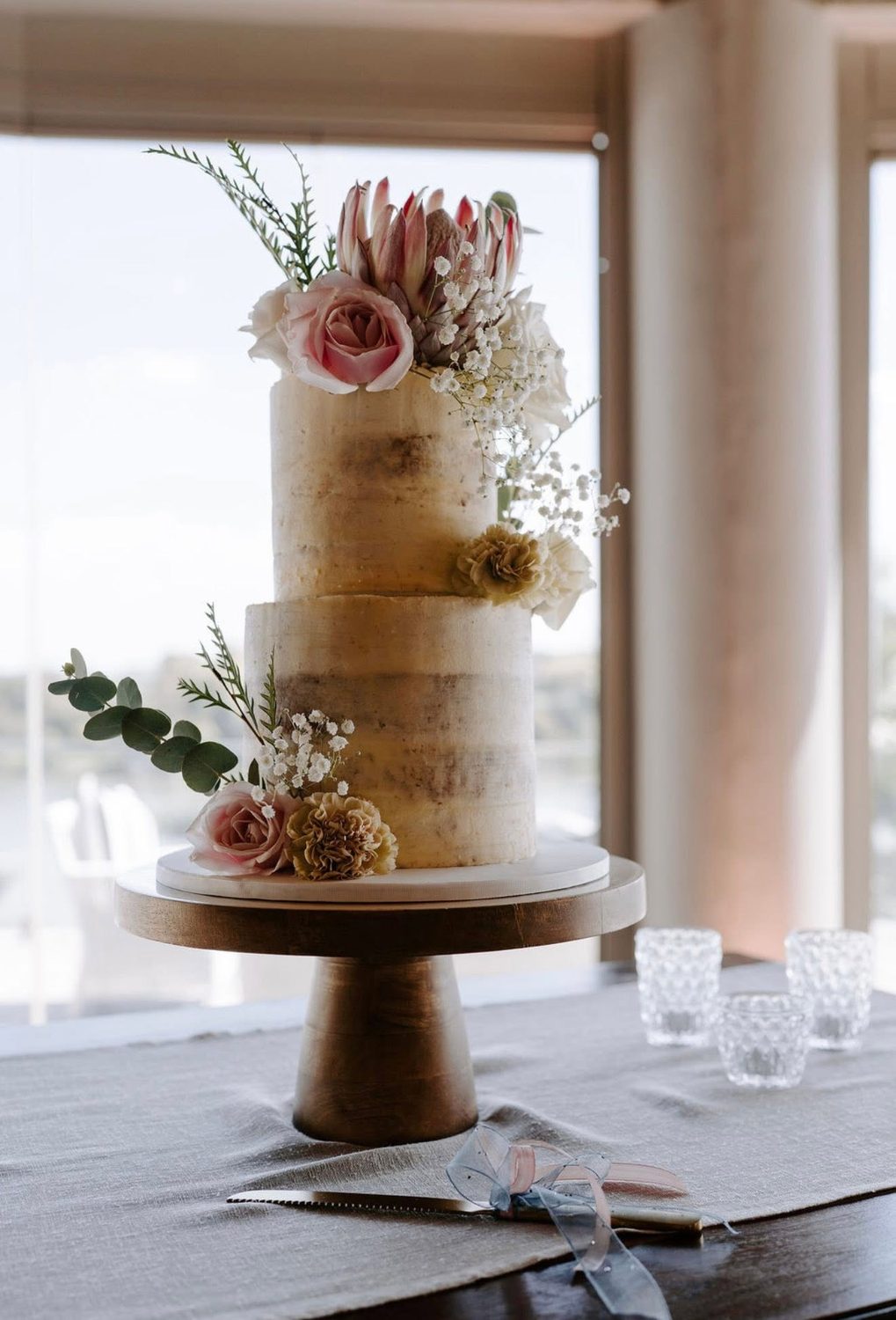 White cake with pink florals on a stand